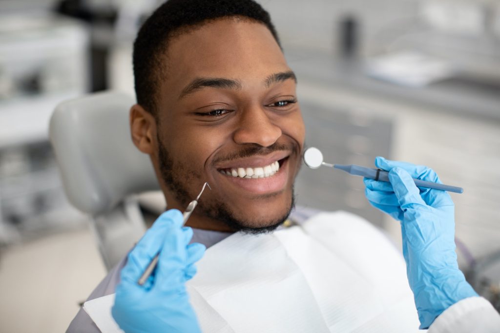 dentistry-services-young-black-male-patient-sitting-in-chair-in-dental-clinic